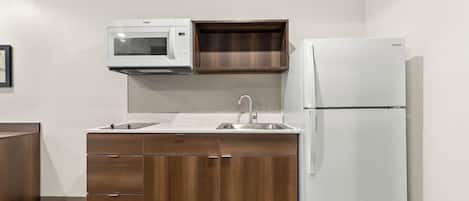A compact kitchen with a microwave, sink, and refrigerator.