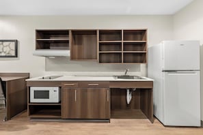 Una cocina equipada con microondas, lavamanos y refrigerador.