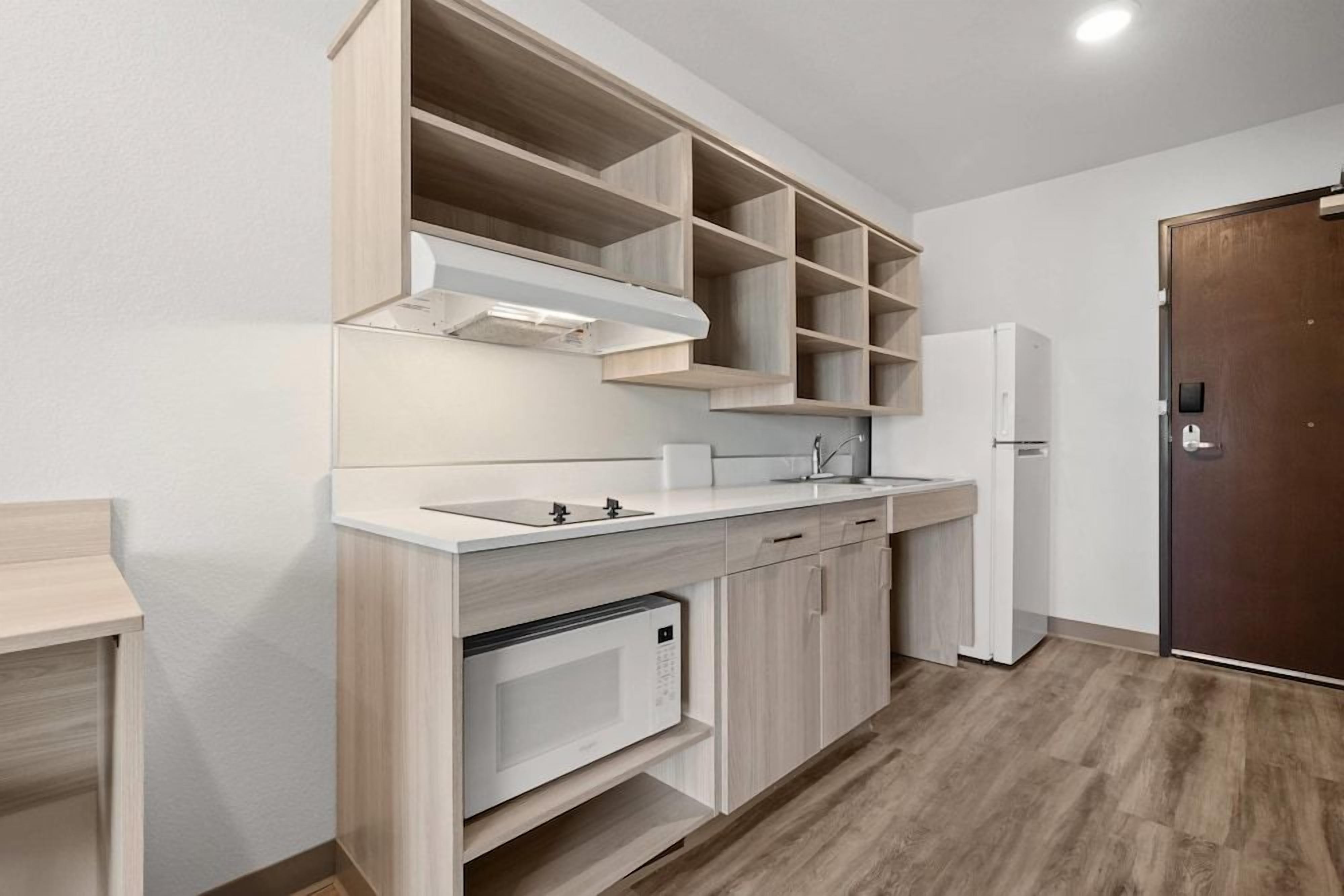 Una cocina moderna con armarios empotrados, un microondas, un fregadero y un refrigerador.