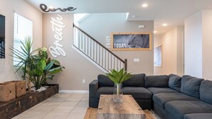 A modern living room with a sectional sofa, a wooden coffee table, and a staircase with a railing.