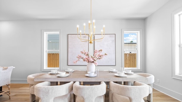 Un coin repas comprenant une table ronde, six chaises, un lustre et une œuvre d’art encadrée accrochée au mur.