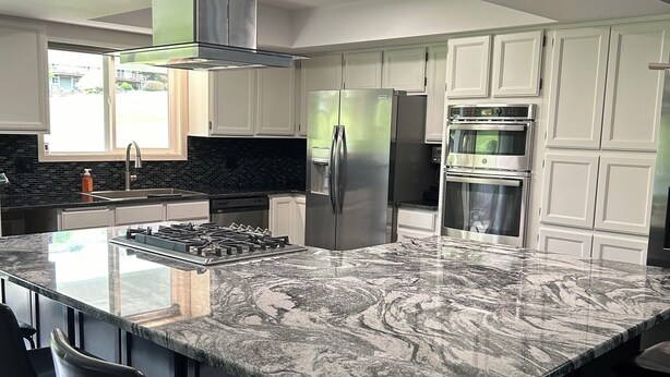 Una cocina moderna con una isla grande, electrodomésticos de acero inoxidable y armarios blancos.