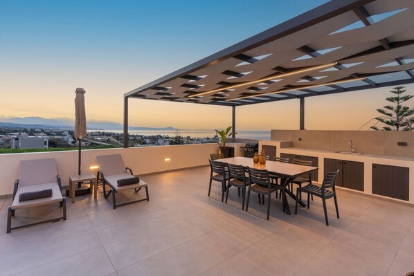 Eine Dachterrasse mit Essbereich, Liegestühlen und Blick auf Stadt und Wasser.
