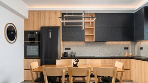 Een moderne keuken met houten kastjes, een zwarte koelkast en een eethoek met houten stoelen.