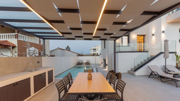 A modern outdoor dining area with a pool, a staircase, and a view of neighboring buildings. - Villa Aelia - With Private Pool and Sauna (Rethymno)