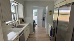 A modern kitchen with white cabinets, stainless steel appliances, and a wooden floor. - Less than 7 minute walk to Siesta Key Beach. (Sarasota)