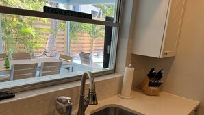A kitchen with a stainless steel sink, a window with a 'BEACH PLEASE' sign, and a ceiling fan. - Less than 7 minute walk to Siesta Key Beach. (Sarasota)