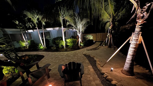 An outdoor patio area with a paved walkway, a wooden bench, and a chair. - Less than 7 minute walk to Siesta Key Beach. (Sarasota)