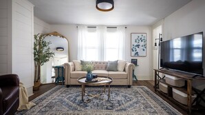 A living room with a beige sofa, a coffee table, a TV, and a large rug. - Walkable to Everywhere in Little Italy- Near CWRU, Cleveland Clinic Main Campus  (Cleveland)