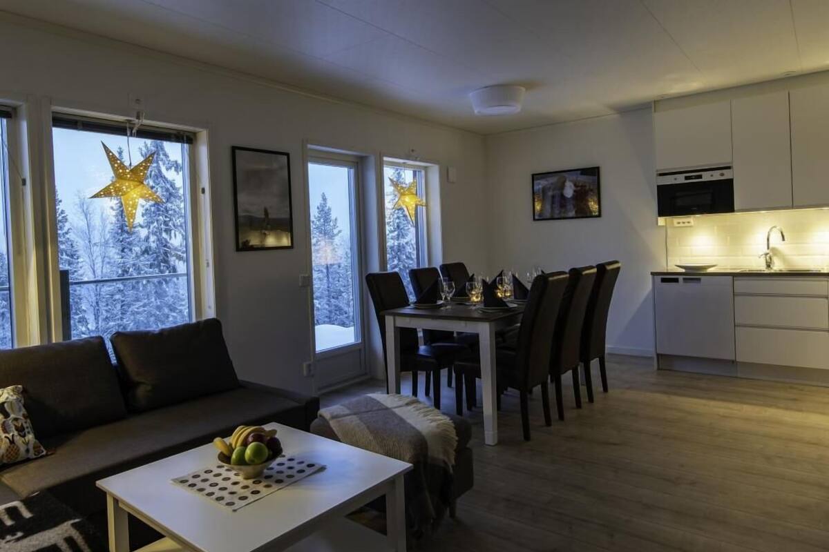 A modern living room with a sofa, dining table, and kitchen area.