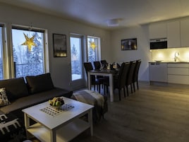 Uma sala de estar moderna com sofá, mesa de jantar e área de cozinha.