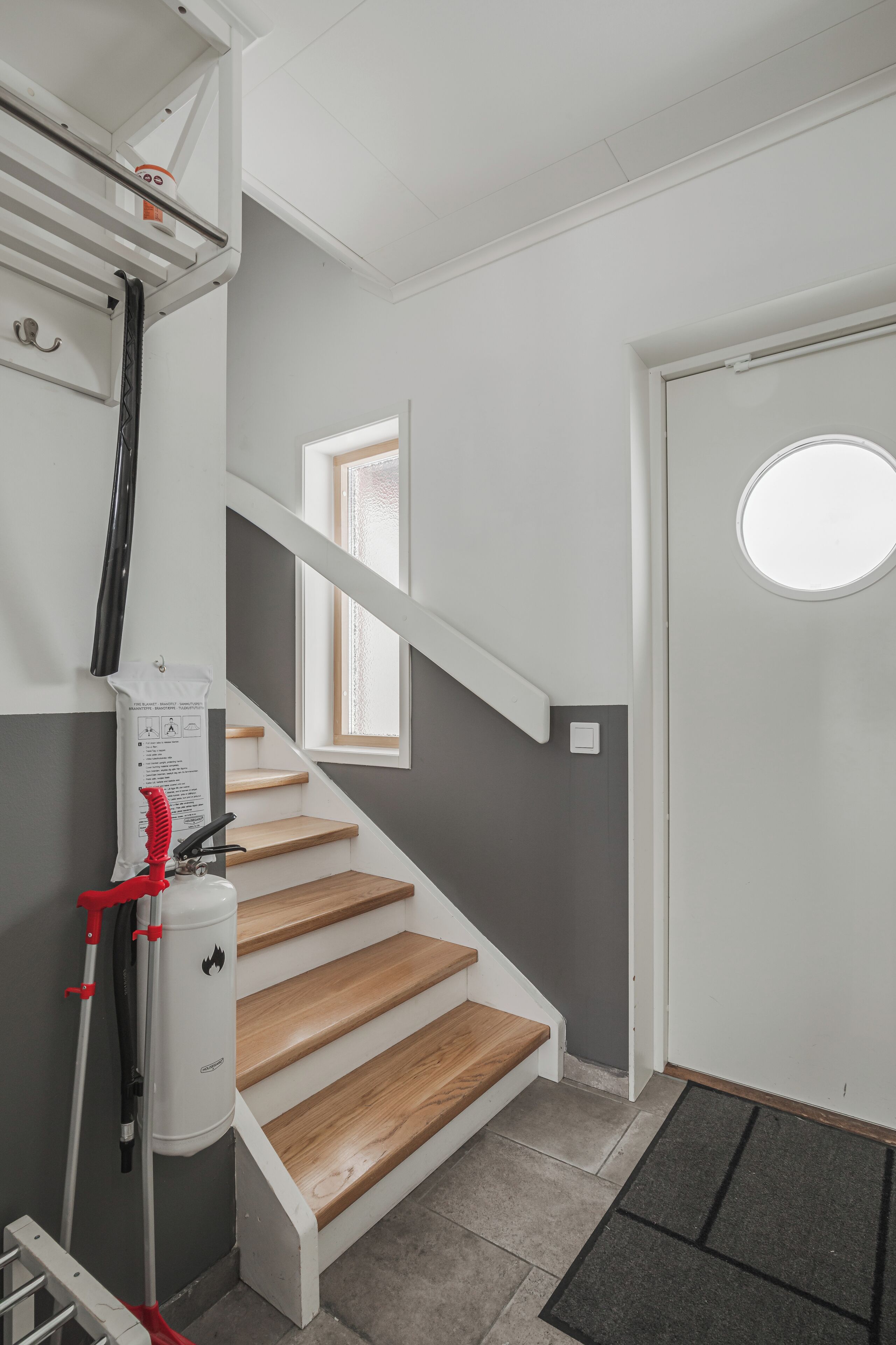 A staircase with wooden steps and a white door with a round window.