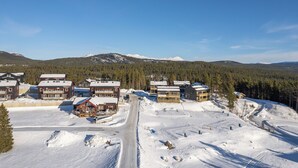 A snow-covered ski resort with multiple buildings, including lodges and cabins, and a clear view of the surrounding mountains. - Parkstigens Lägenheter (Funasdalen)