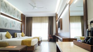 A hotel room with a bed, a desk, a chair, a coffee machine, and a TV. - Highland Hotel (Bengaluru)