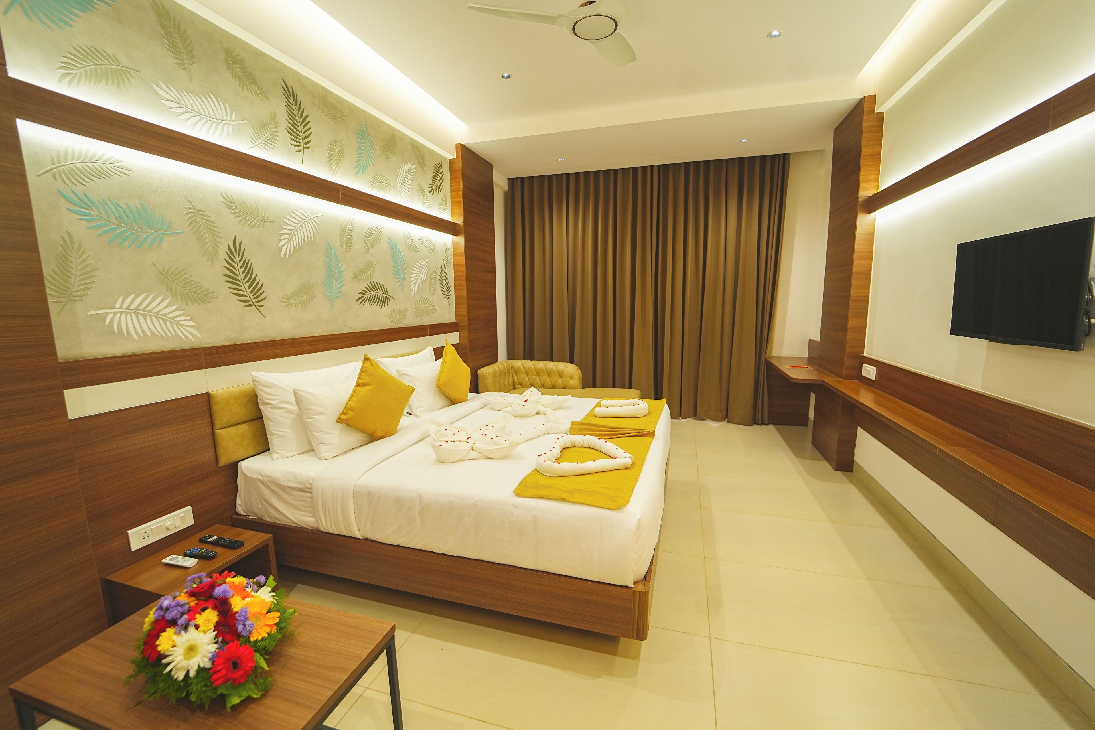 A modern hotel room with a bed, bedside table, and a TV on the wall.