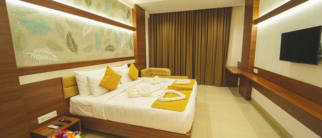 A modern hotel room with a bed, bedside table, and a TV on the wall.