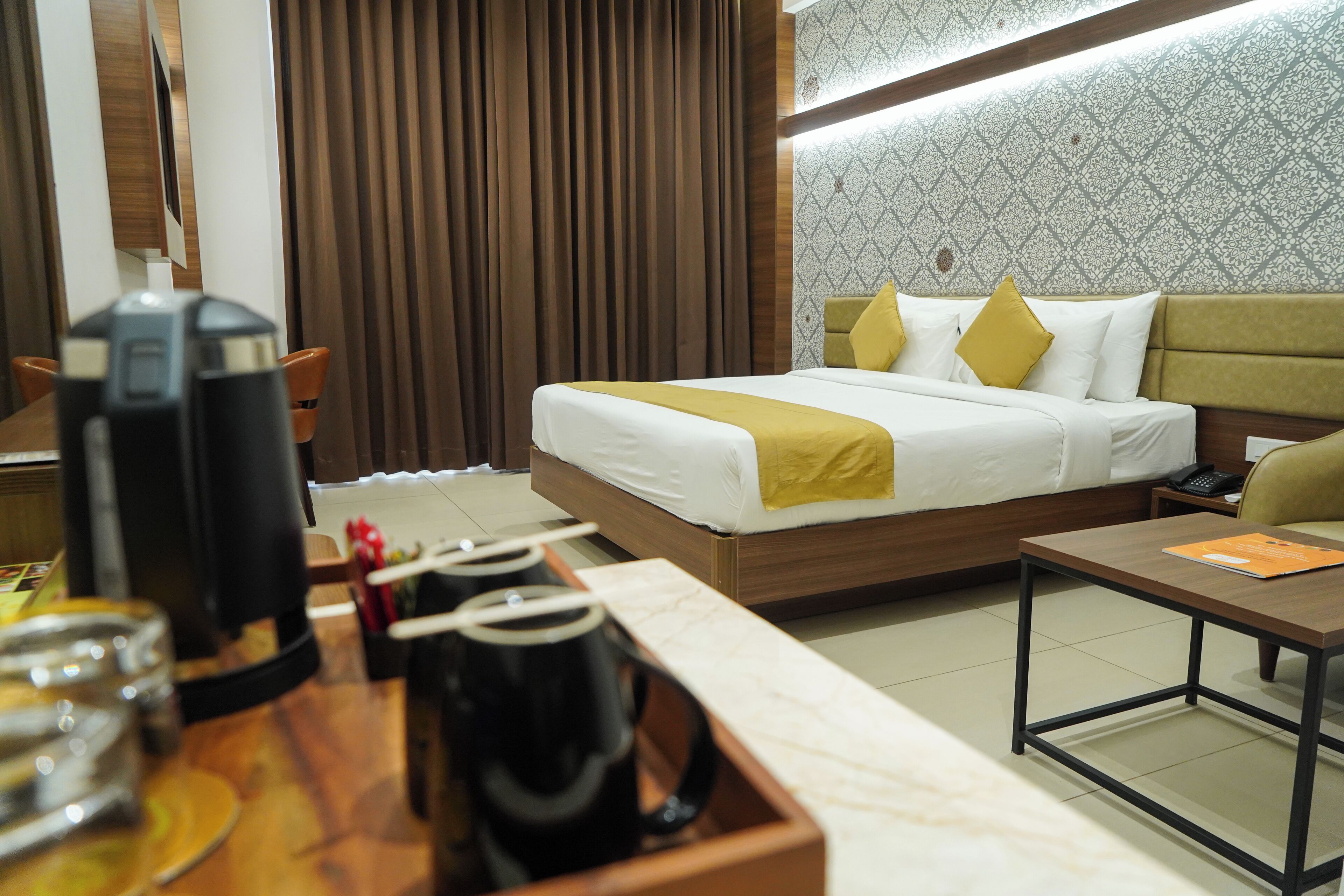 A hotel room with a bed, bedside table, and a coffee station.