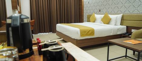 A hotel room with a bed, bedside table, and a coffee station.