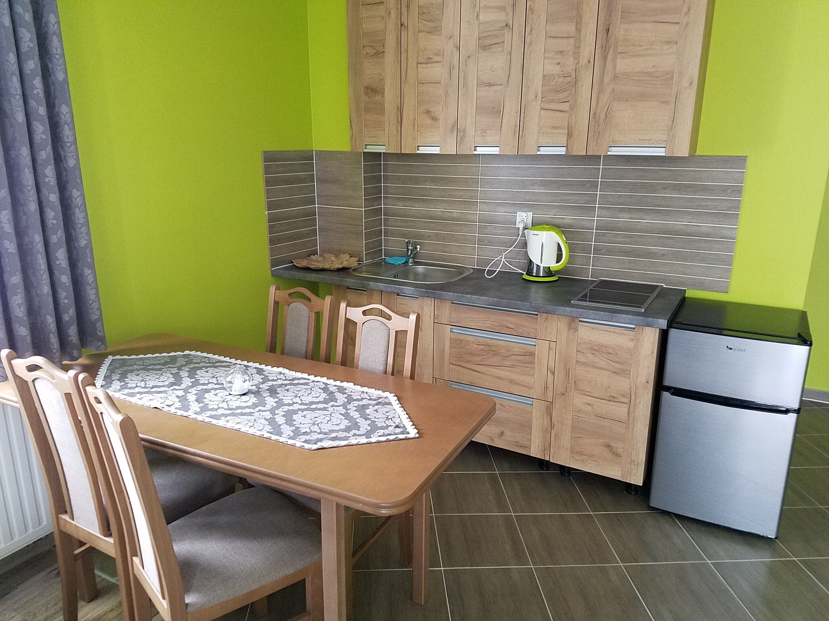 Une cuisine compacte avec des meubles de rangement en bois, un petit plan de travail et un réfrigérateur encastré.