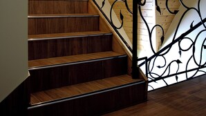 Un escalier en bois avec une rampe en fer forgé noir.