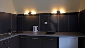 Une cuisine moderne avec des meubles de couleur bois foncé, un plan de travail blanc, une bouilloire et un lave-vaisselle encastré.