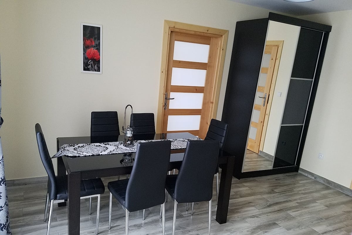 A dining area with a table, chairs, a window, and a wardrobe.
