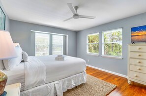 A bedroom with a bed, a ceiling fan, two windows with blinds, a dresser, and a painting on the wall. - Came & Stayed, Community Pool, Tranquility, Beach Gear Credit Included! (St George Island)