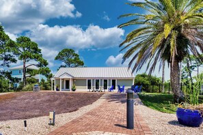 A building with a covered patio area, outdoor seating, and a palm tree. - Came & Stayed, Community Pool, Tranquility, Beach Gear Credit Included! (St George Island)
