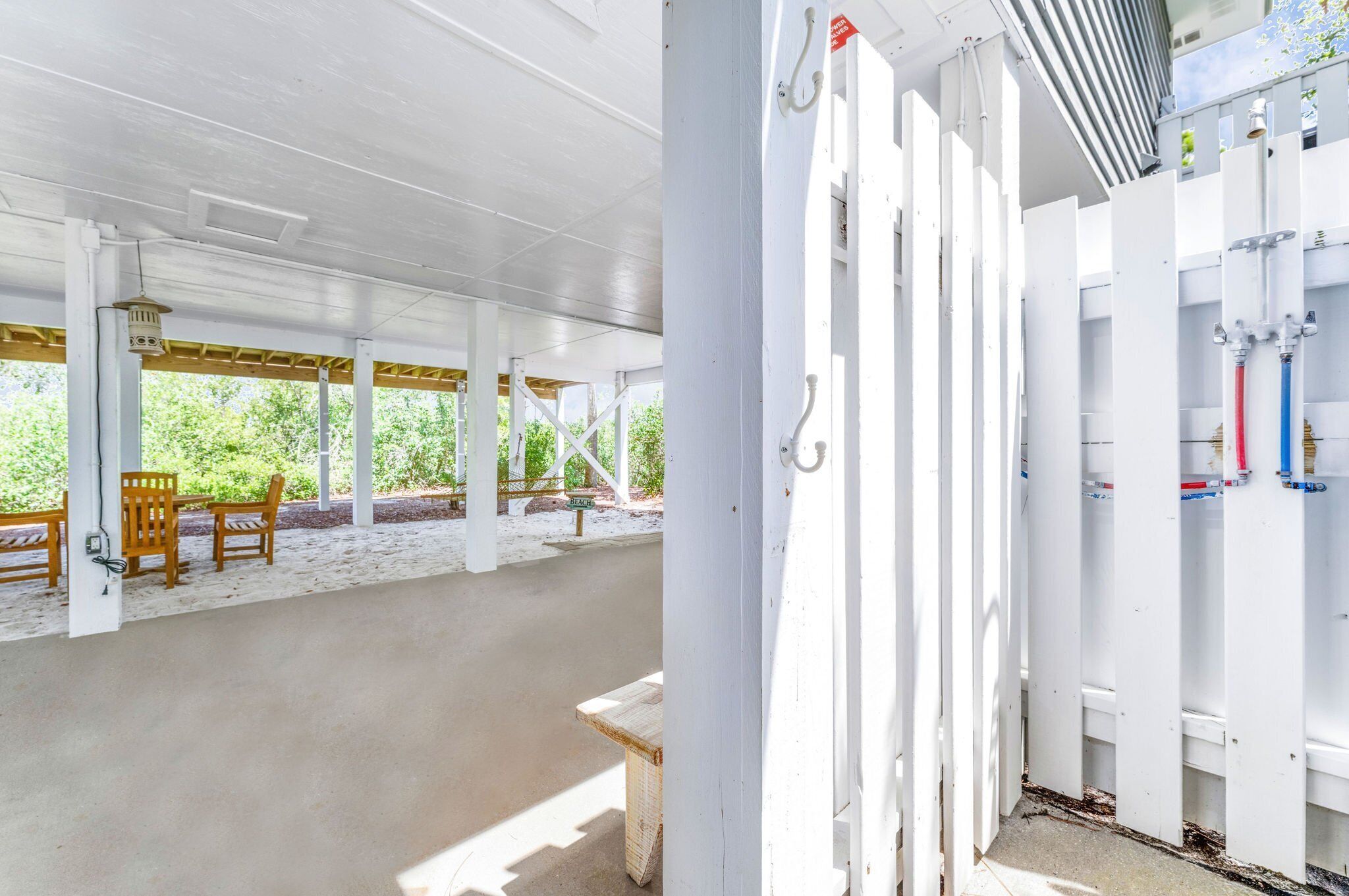 Un espace extérieur abrité, doté de bancs en bois et d’une table de pique-nique, de piliers blancs et d’un système de filtration de l’eau.