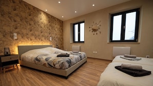 A bedroom with two beds, a stone wall, and a clock on the wall.