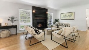 Una sala de estar moderna con chimenea, dos sofás, una mesa de centro y una mesa de comedor.