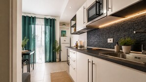 Een moderne keuken met witte kastjes, een zwart aanrecht, een ingebouwde magnetron en een backsplash van steen.