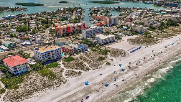 Vista aérea de una zona costera con playa, edificios y cuerpos de agua.