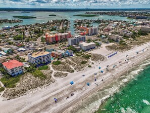 An aerial view of a coastal area with a beach, buildings, and water bodies.