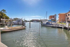 A marina with boats docked, a clear sky, and buildings in the background.