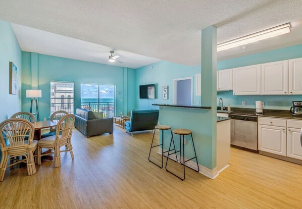 A spacious living area with a dining set, a sofa, and a TV.