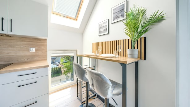 A modern kitchen with a wooden countertop, a built-in bench, and a potted plant. - Apartamenty Sun & Snow Na Różanej (Ustronie Morskie)