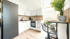 A modern kitchen with white cabinets, a black refrigerator, a built-in oven, and a wooden countertop. - Apartamenty Sun & Snow Na Różanej (Ustronie Morskie)