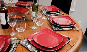 Une table à manger dressée avec des assiettes rouges, des verres à vin et une bouteille de vin.