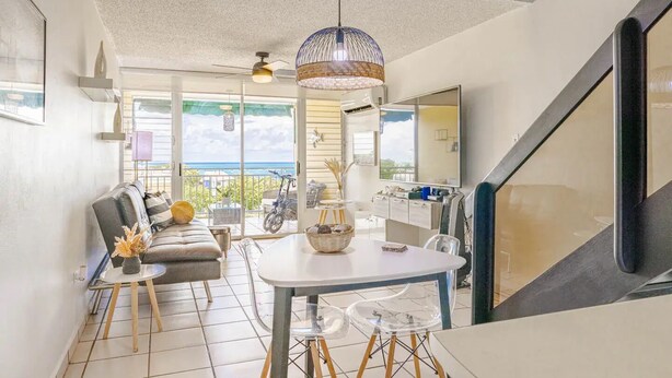 Uma sala de estar moderna com área de jantar, janelas amplas e vista para o exterior.