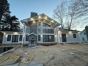 A two-story house with a stone fireplace, multiple windows, and a well-lit exterior.