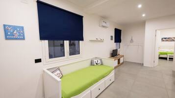 Een kinderkamer met een stapelbed, een raam met zonwering, een radiator en een klein plankje met spullen.