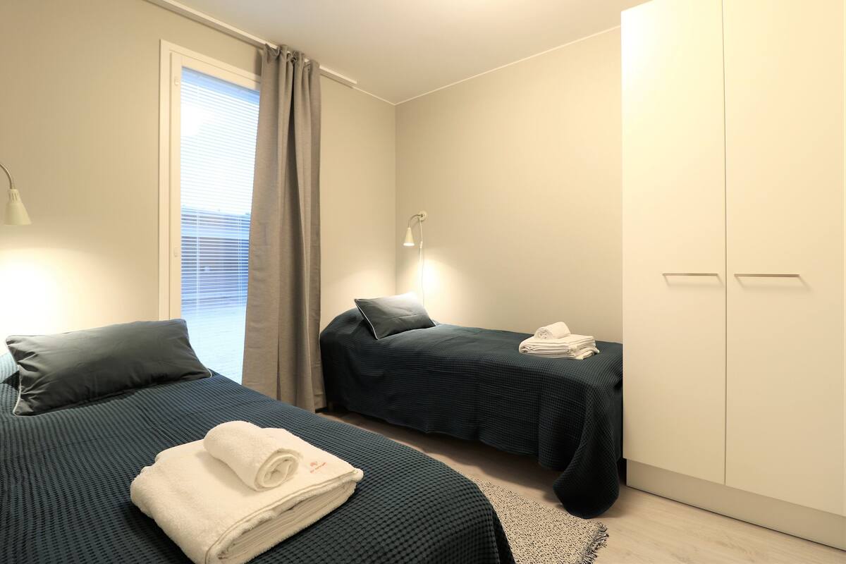 Un dormitorio con dos camas, un armario y una ventana con cortinas.