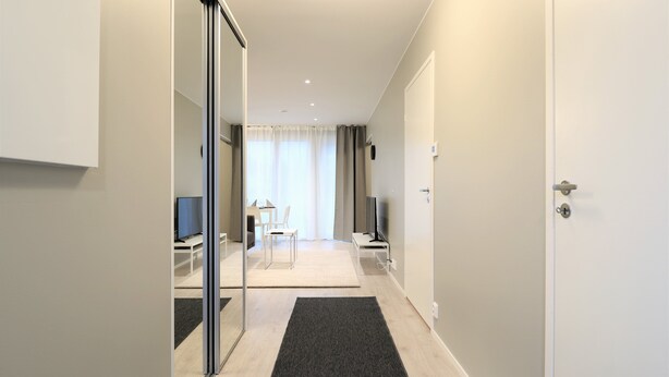 A modern hotel room with a glass door leading to a living area, a flat-screen TV, a small table, and a chair. - Forenom Serviced Apts Espoo Perusmäki 2 (Espoo)