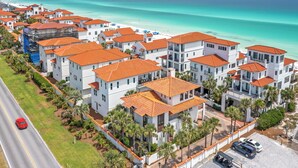 Une zone résidentielle côtière avec des bâtiments blancs et des toits orange, une plage et une mer d’un bleu limpide.