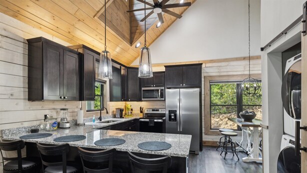 A modern kitchen with dark cabinets, granite countertops, and stainless steel appliances.