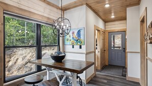 A modern kitchen with a wooden table, a bowl, and a painting of a rooster.