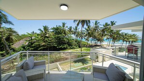 A balcony with wicker furniture and a view of the beach and palm trees. - 0048 Affordable Condo in the Beach (Cabarete)