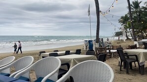 A beachside restaurant with outdoor seating, tables, and chairs, overlooking the ocean. - 0048 Affordable Condo in the Beach (Cabarete)