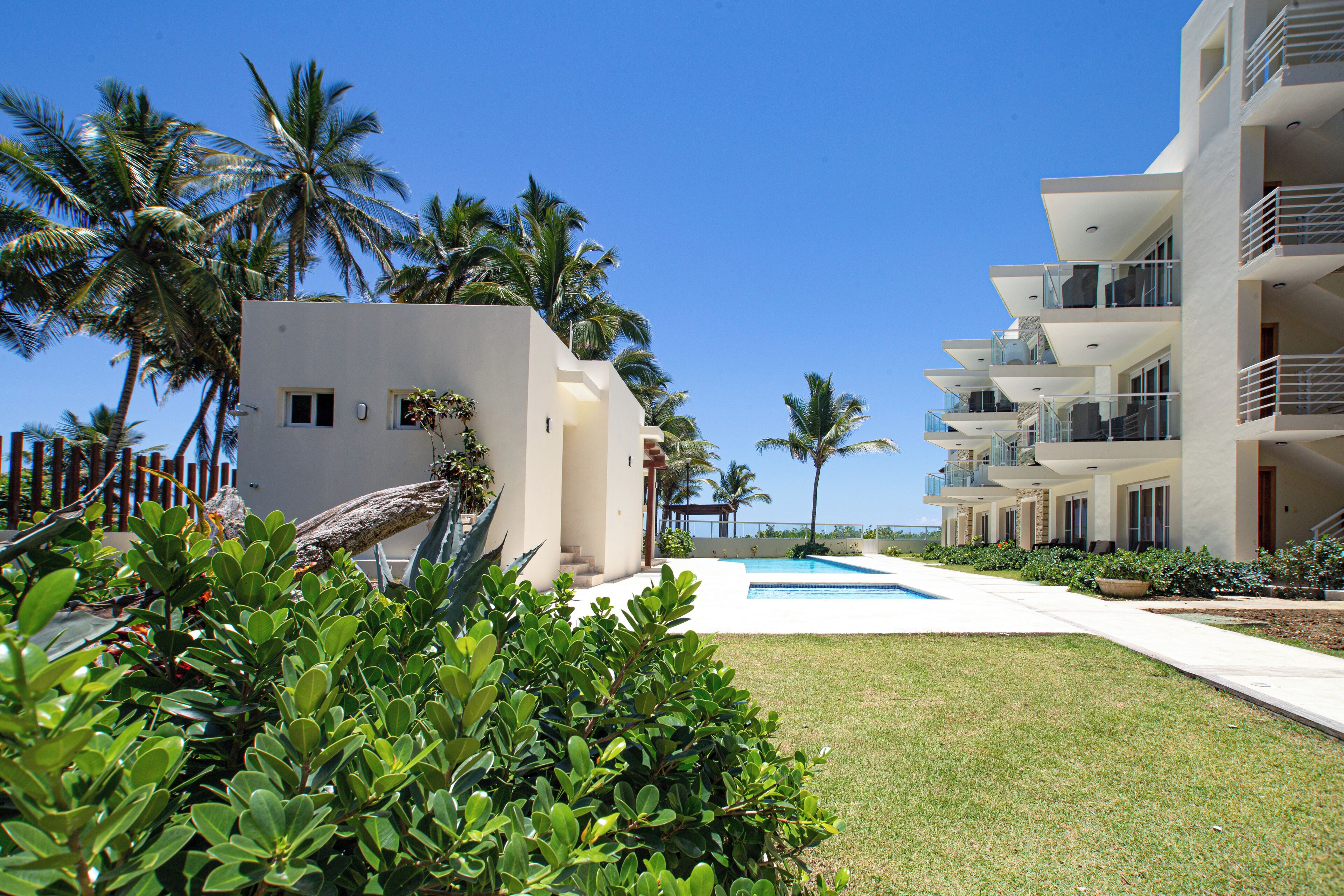 A resort with a swimming pool, palm trees, and modern buildings.